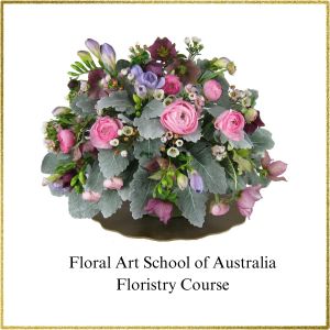 Table Centrepiece of mixed flowers.This design features pink ranunculus, pale pink and deep pink helleborus (also known as winter roses) mauve freesias, waxflower and velvety grey-green lambs ears foliage.